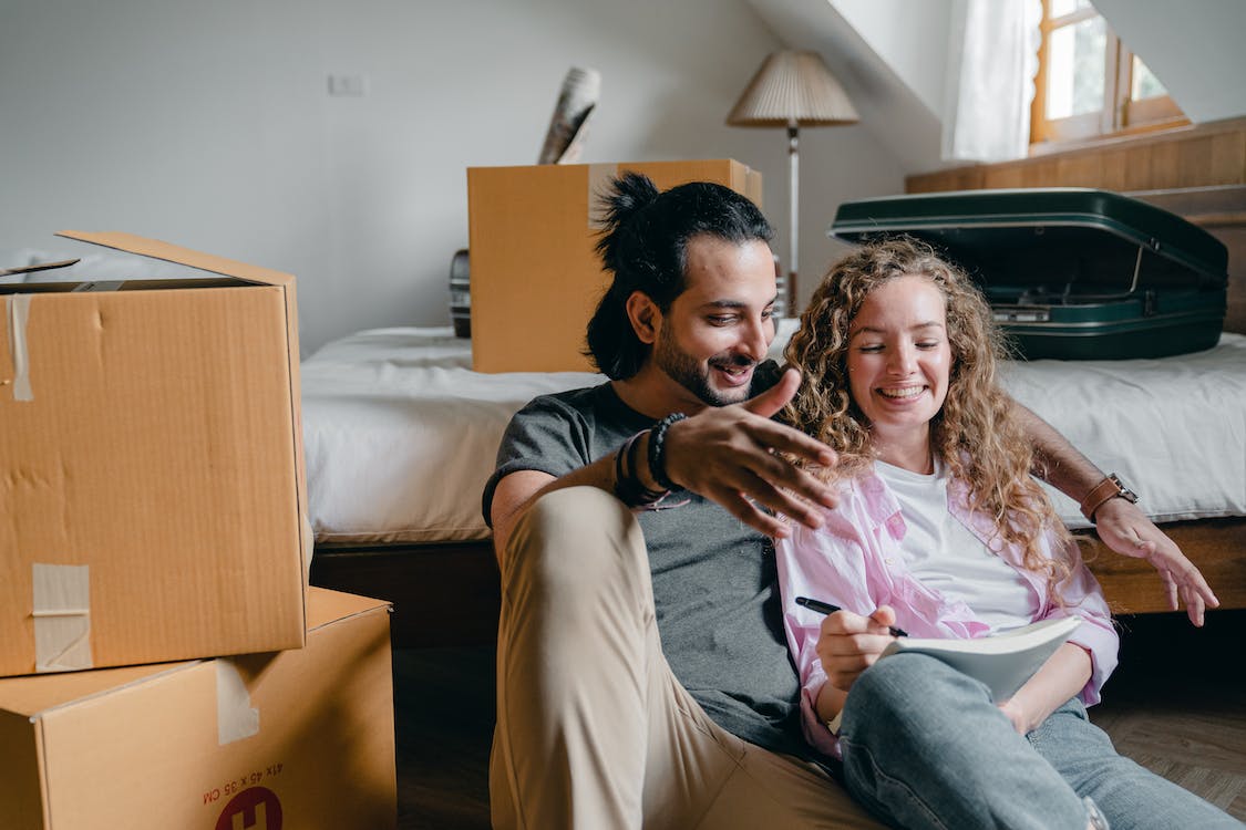 Free Cheerful couple taking notes while moving to new house Stock Photo
