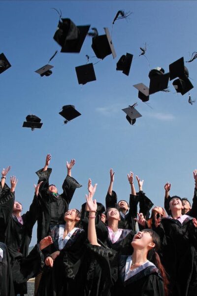 Free Newly Graduated People Wearing Black Academy Gowns Throwing Hats Up in the Air Stock Photo
